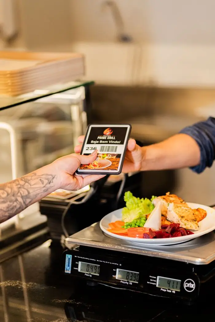 Customer purchasing a meal at a deli counter, showcasing food weighing and transaction exchange.