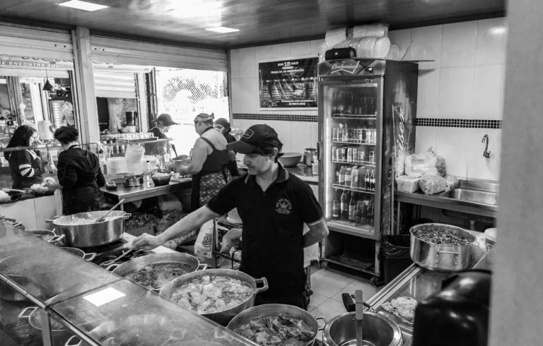 A dynamic black and white photo of a busy kitchen with chefs cooking and preparing food.