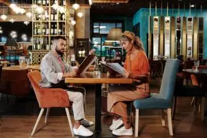 Couple sitting together at a stylish restaurant reviewing the menu, creating a warm and inviting atmosphere.